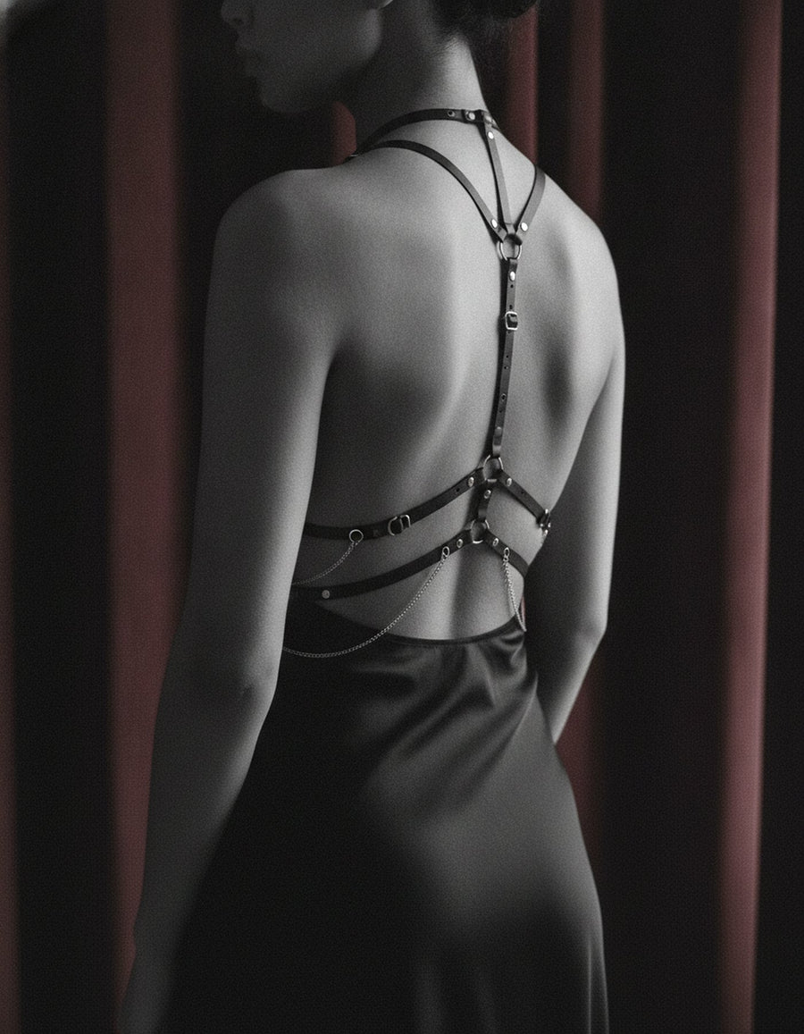 Woman seen from behind wearing a black leather strappy harness
